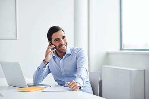 a man in a blue shirt talking on his cell phone