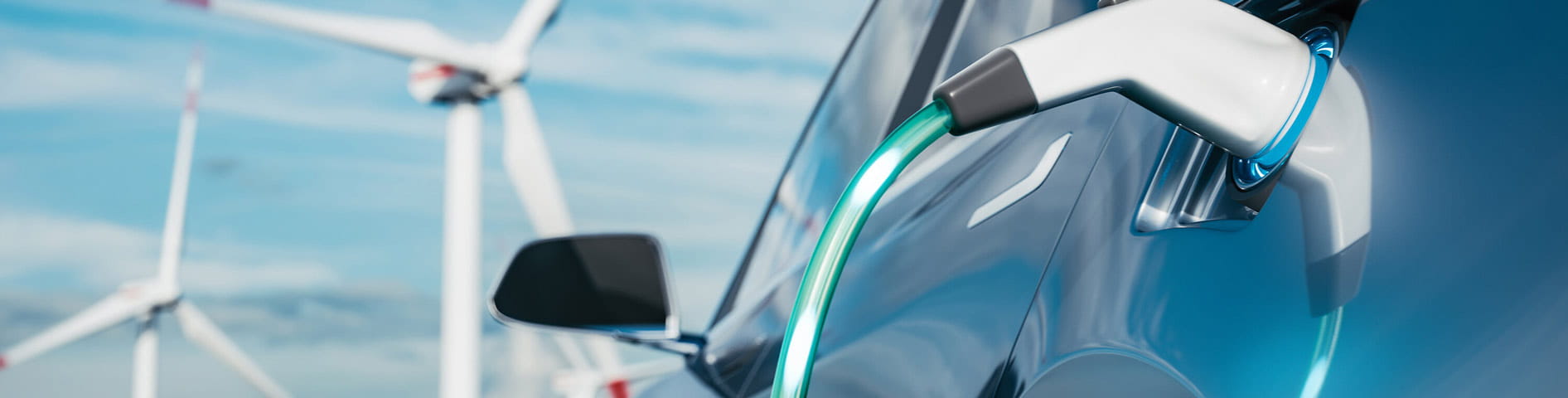 E-Auto beim Laden vor Windrädern