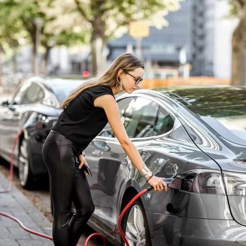 Frau beim Laden eines Elektroautos