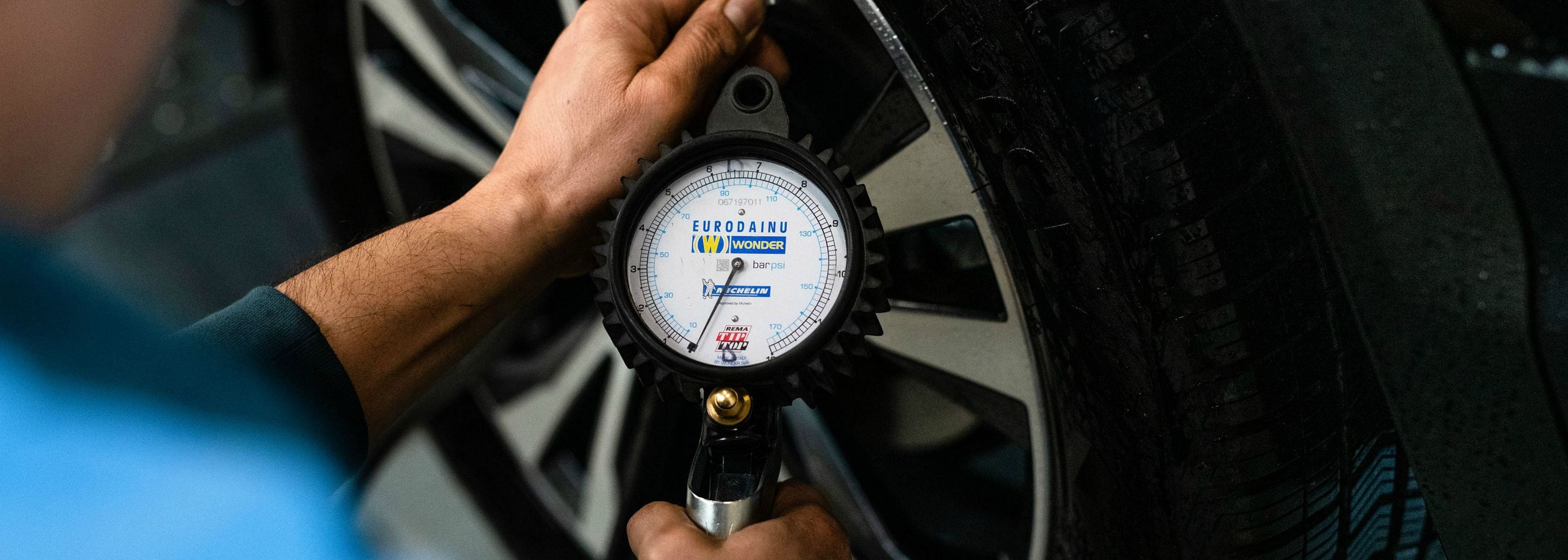 man measures tyre pressure