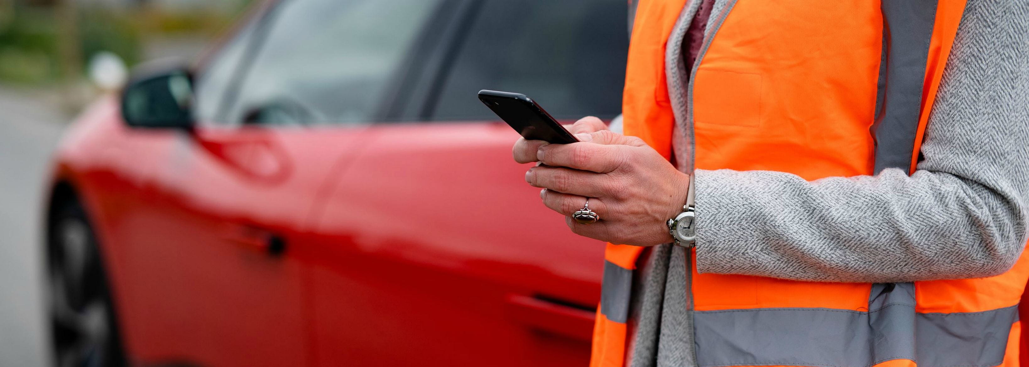 Man holding a phone in front of a car