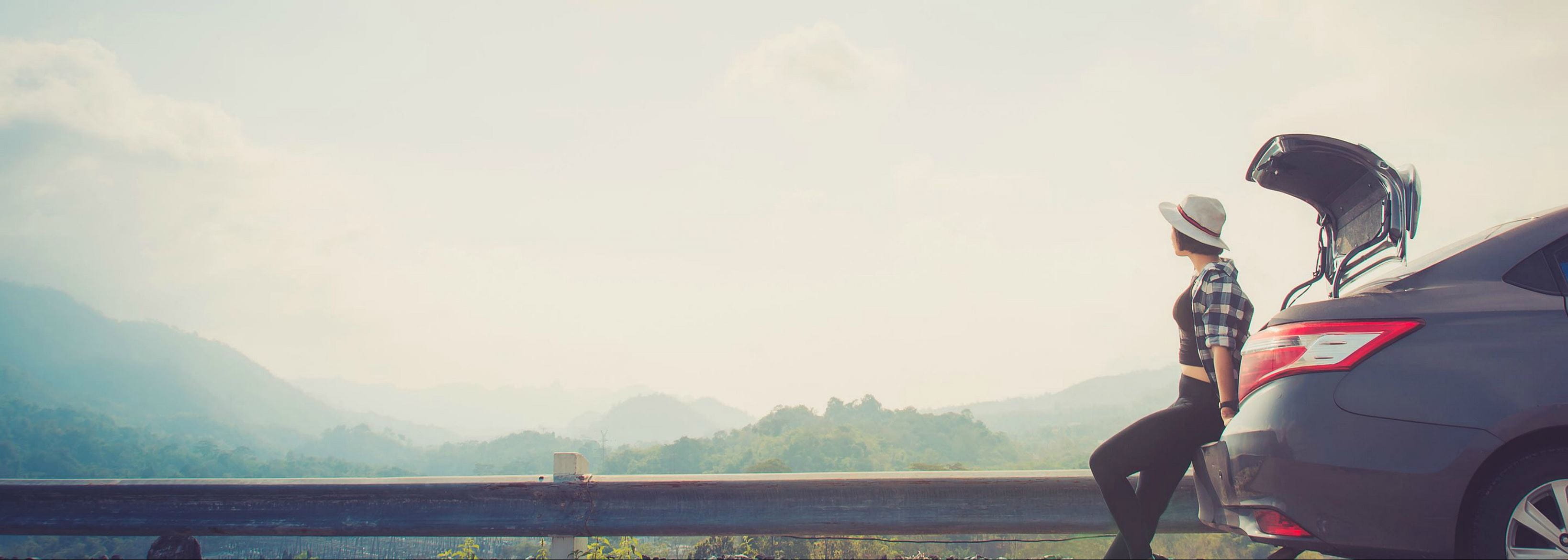 Woman stands on the back of a car