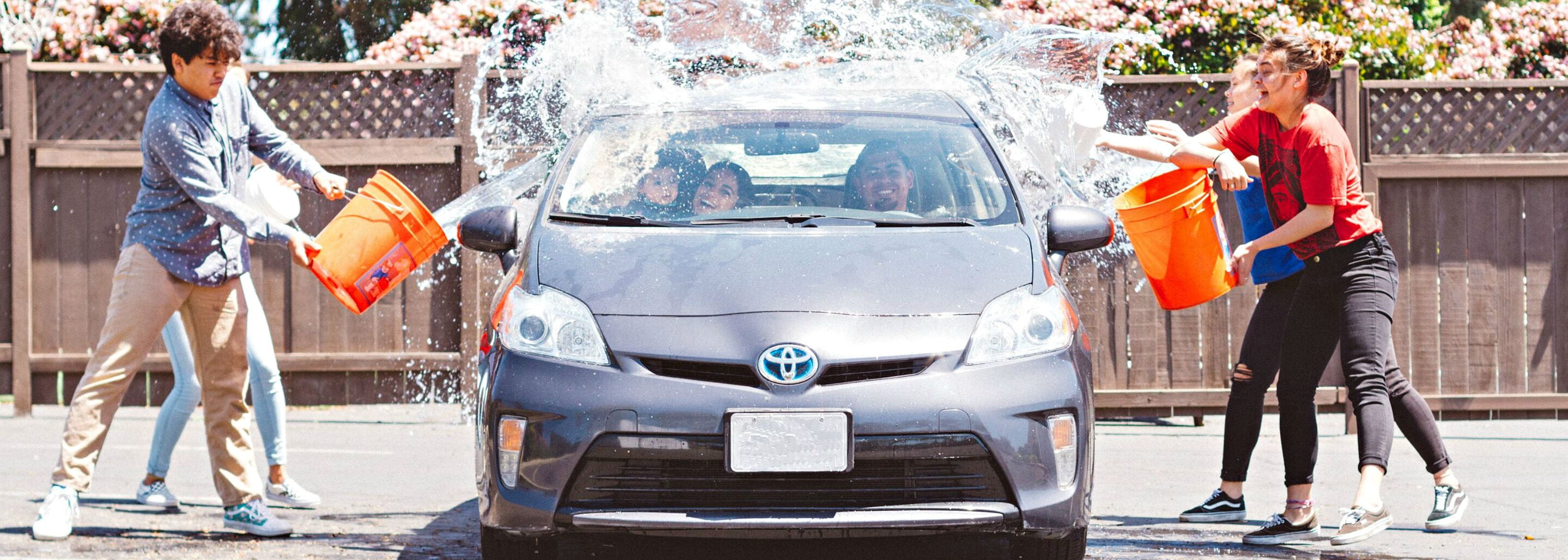 Happy people throwing water on a car