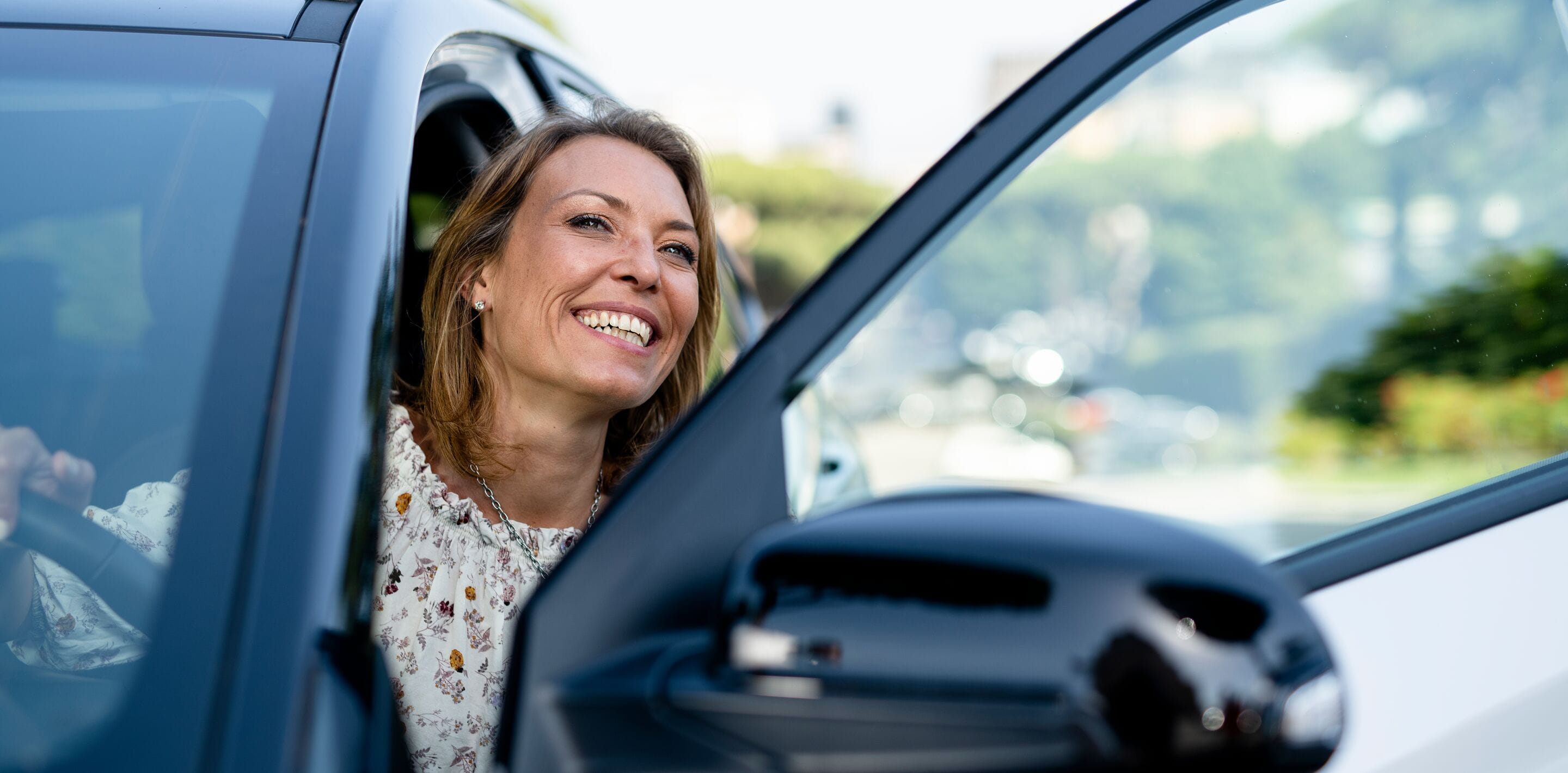 Woman smiling on driver's seat with the door open