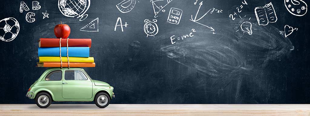 car with books on top in front of a blackboard