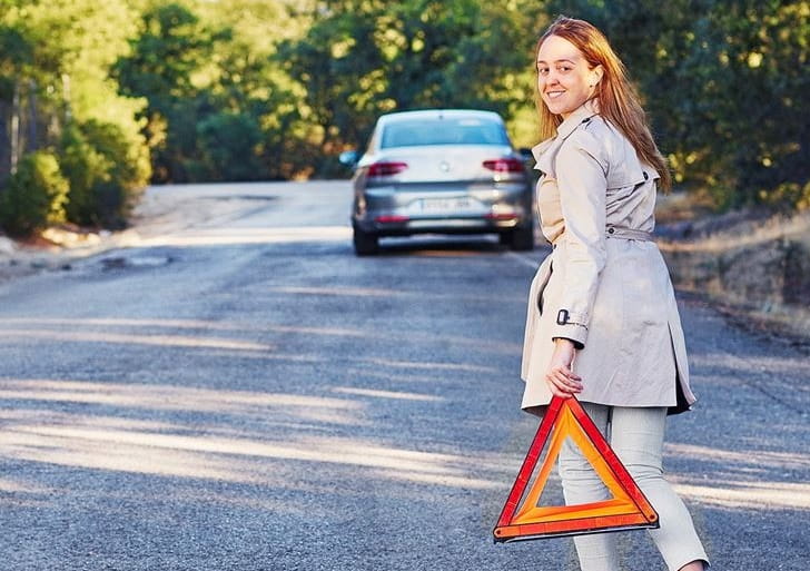Breakdown on side of road - woman carrying orange triangle low