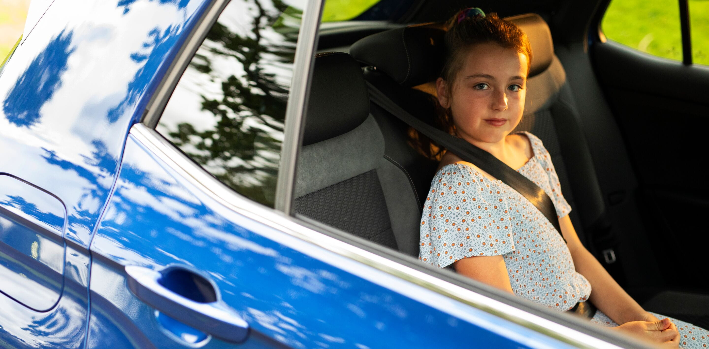 Child in backseat of a blue car