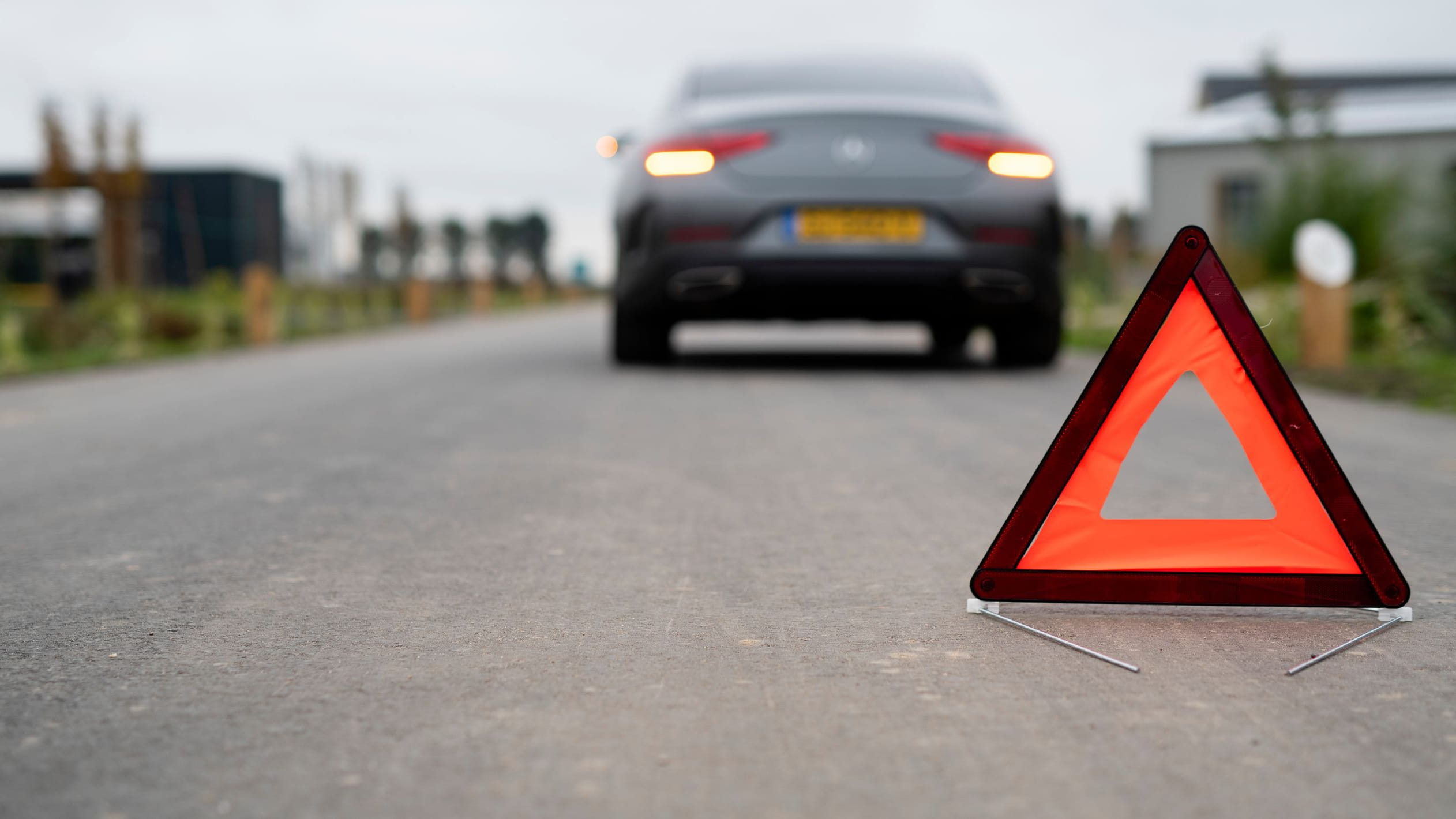 Warning triangle on road with car in background