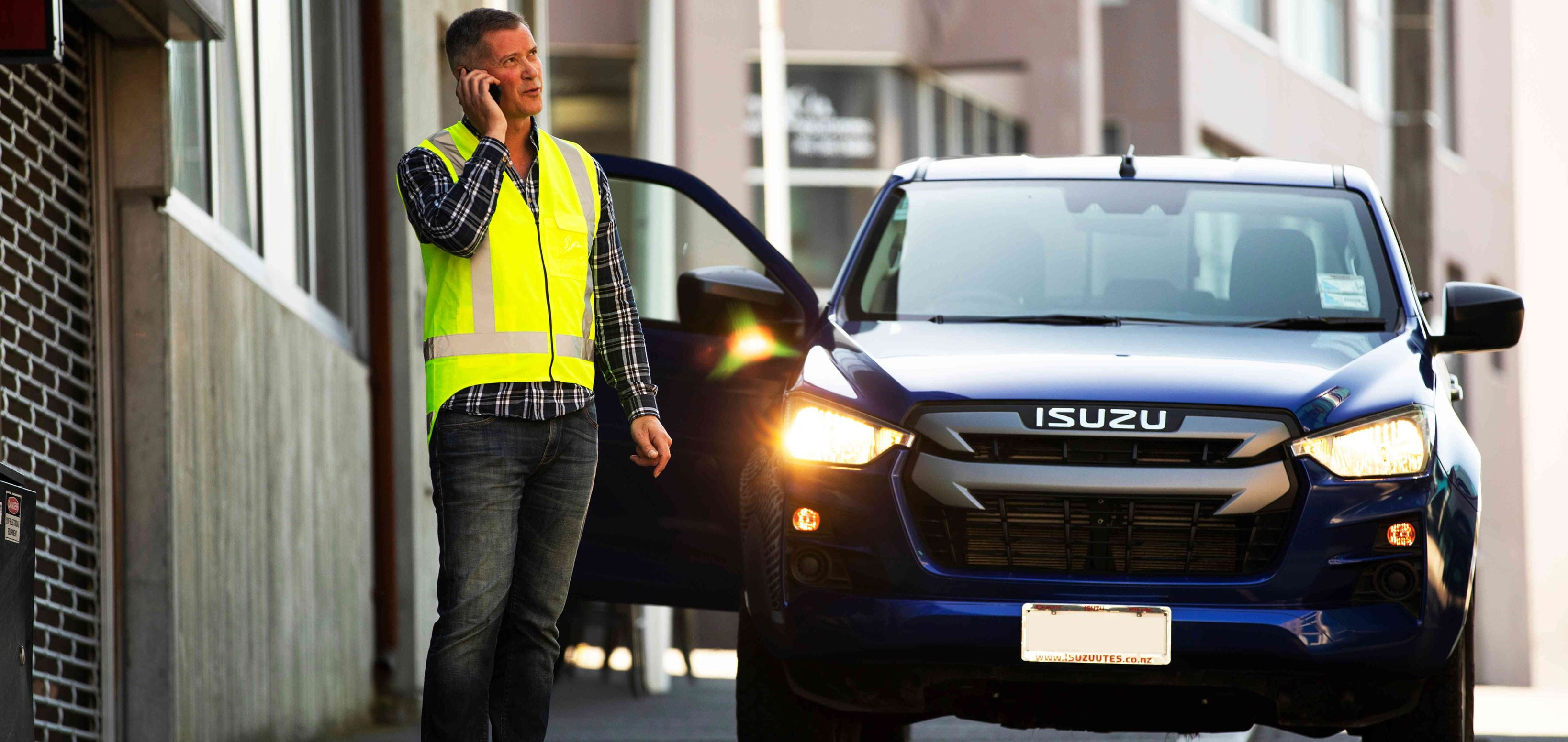 A man talking on the phone in front of a blue LCV