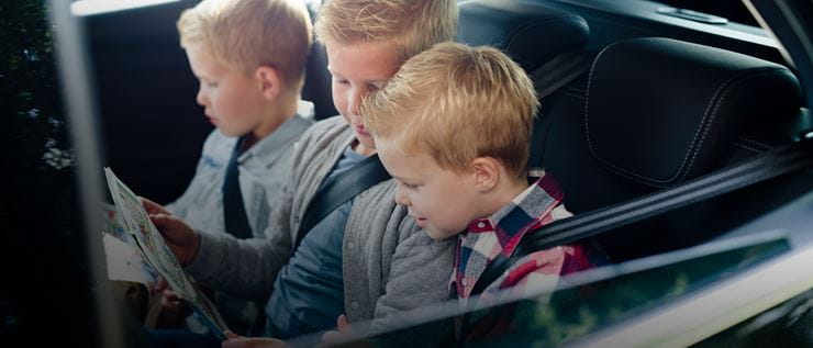 Close up - three children in back seat reading