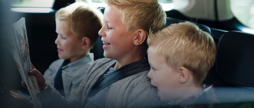  three children in back seat reading