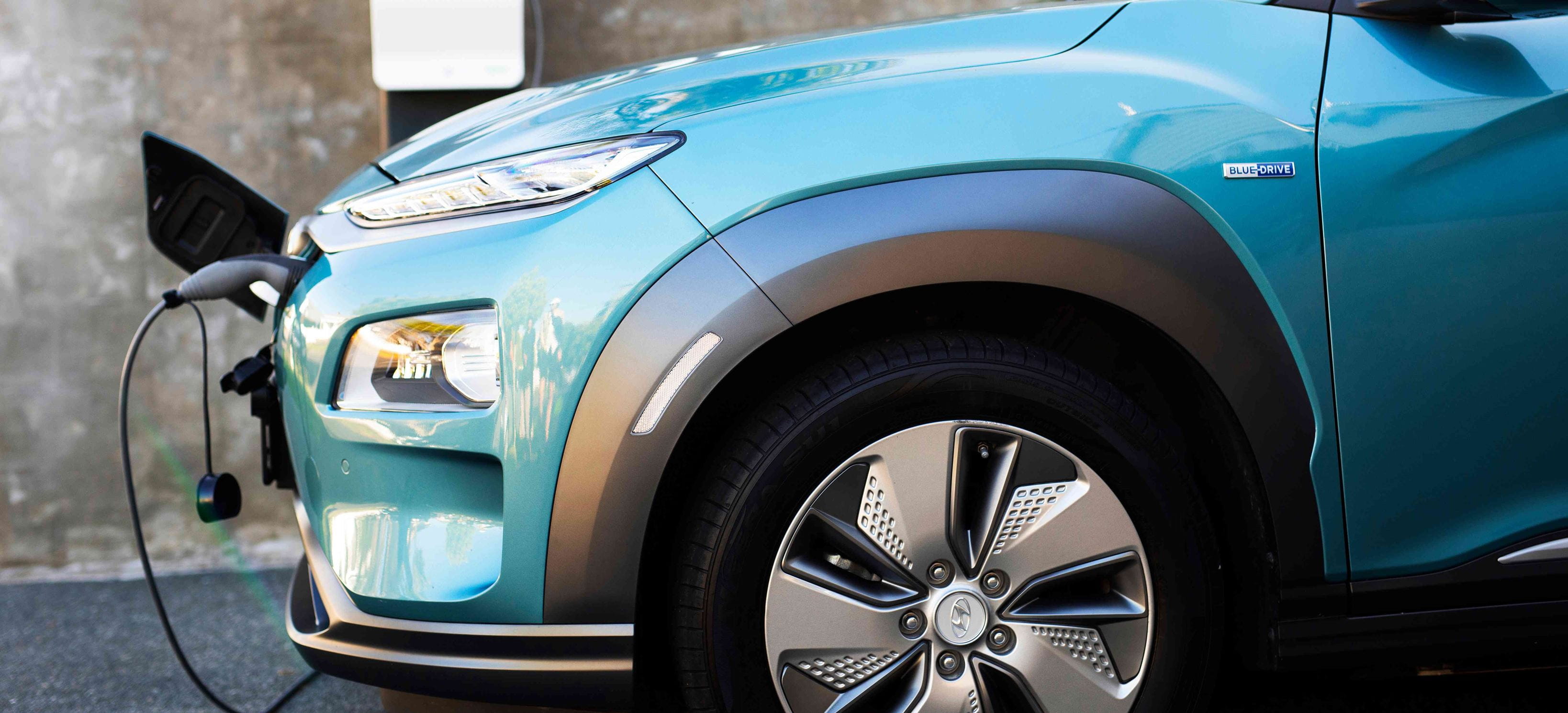 A turquoise car connected to an EV charger