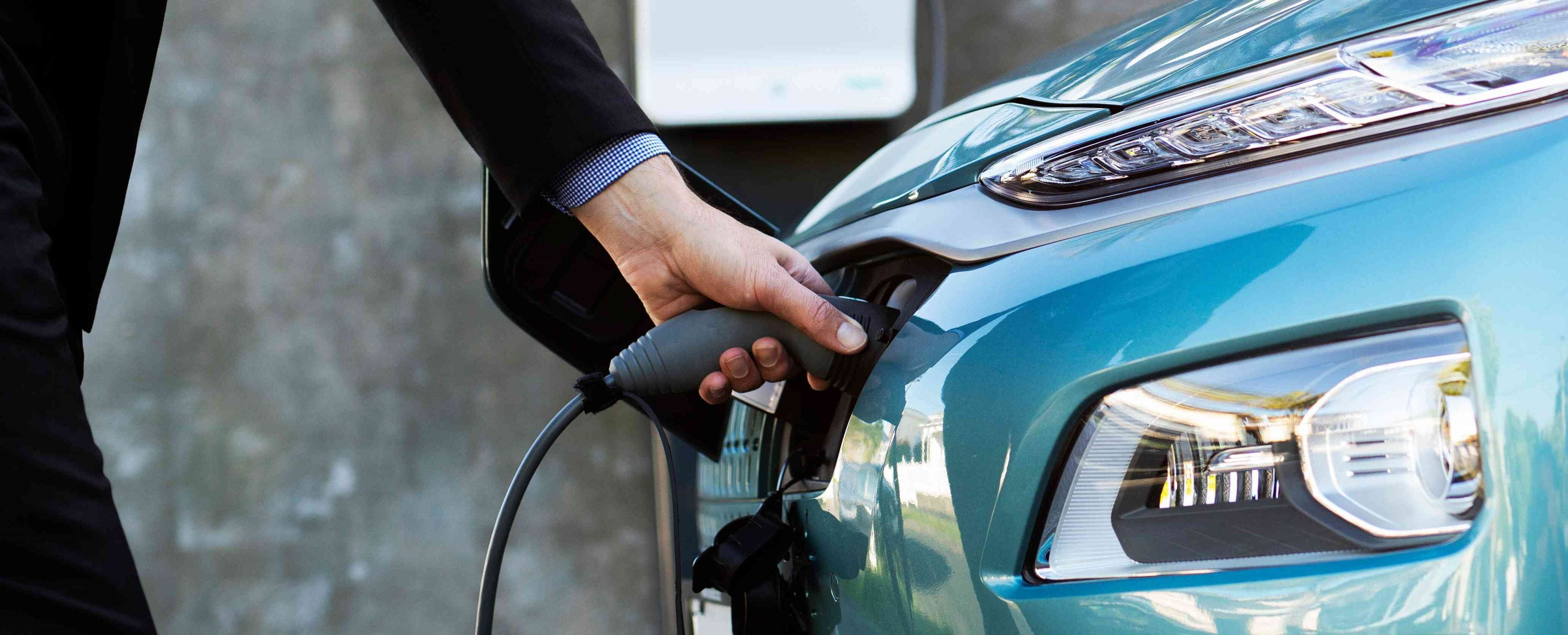 Close up - man in a black suit is charging an electric vehicle