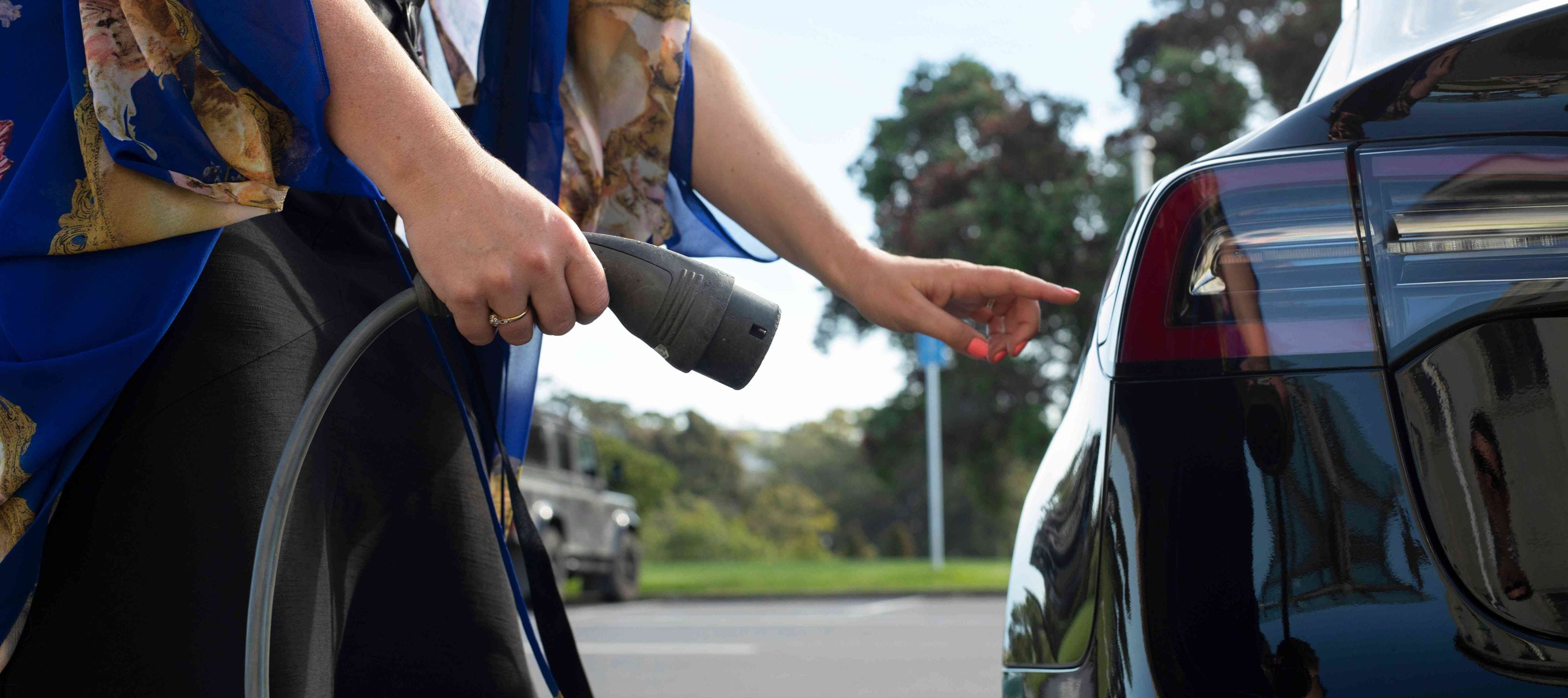 Close up - woman plugging in the car at an EV charging station