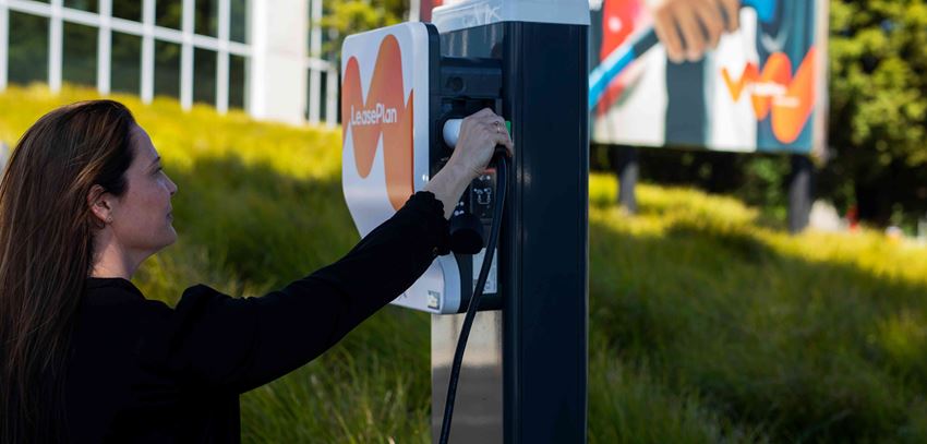 Close up of a woman plugging her vehicle into LeasePlan branded charger
