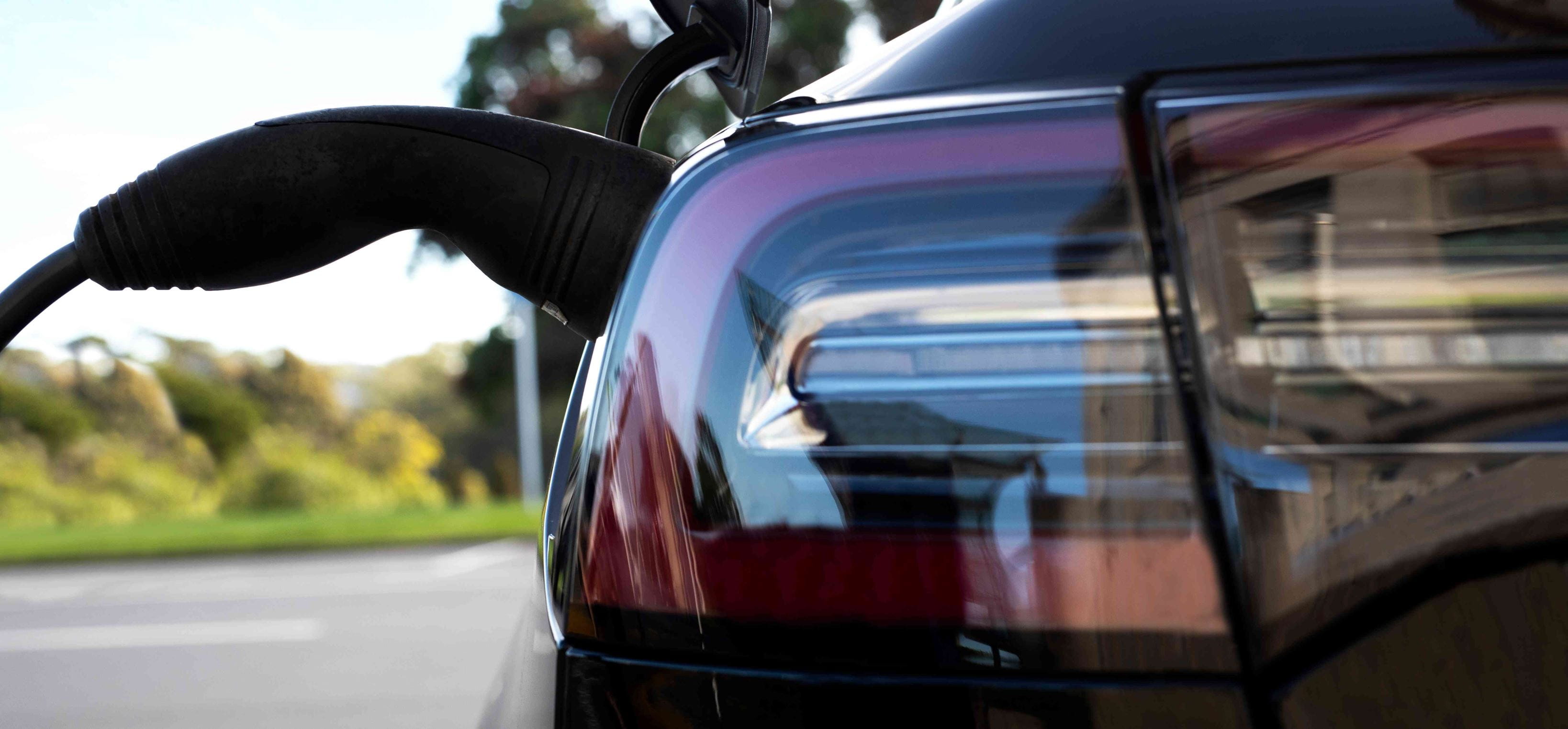 Close up of a dark vehicle connected to EV charger