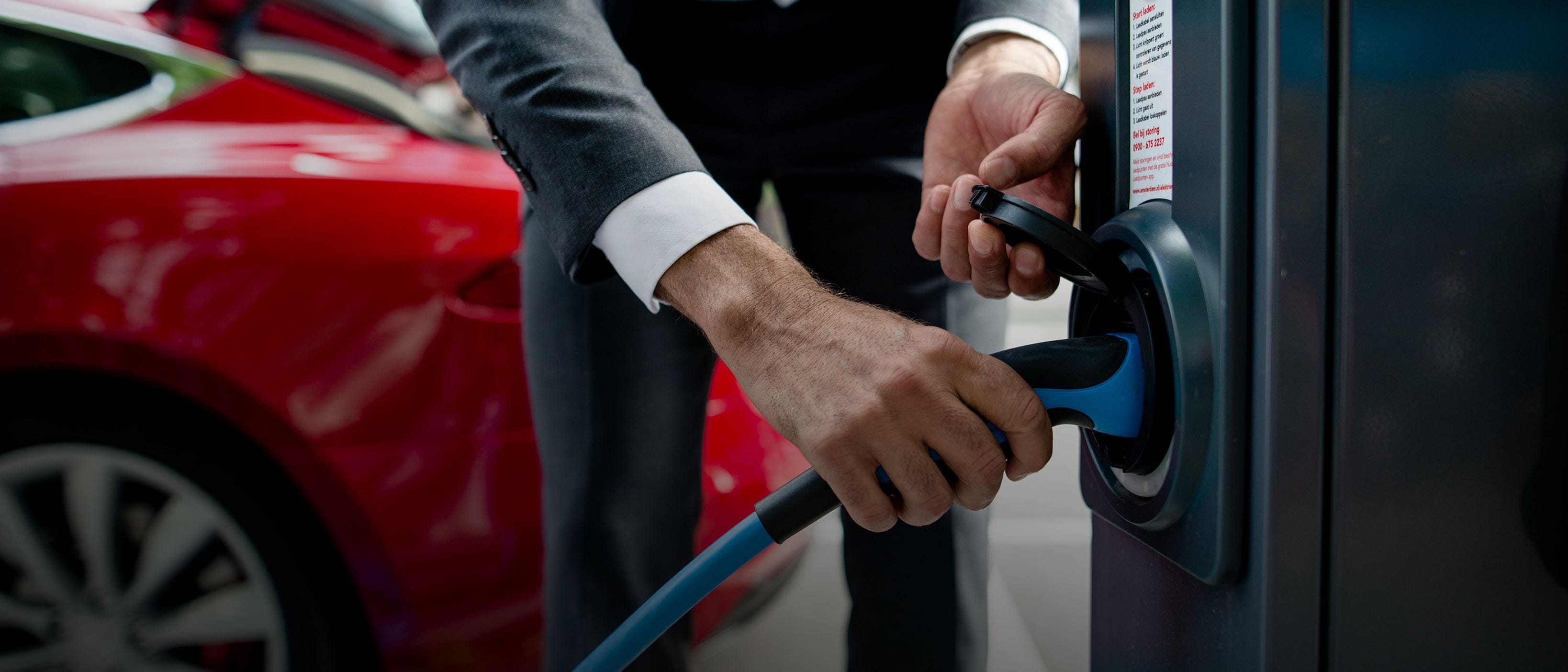 Close up of man plugging in EV to street charger