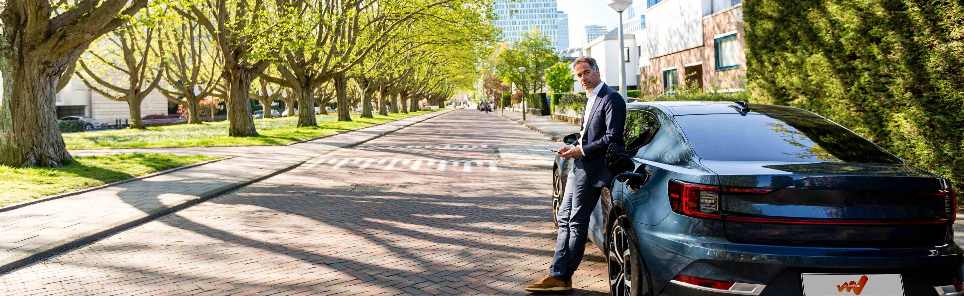 Man leaning against charging Polestar 2 on residentual street