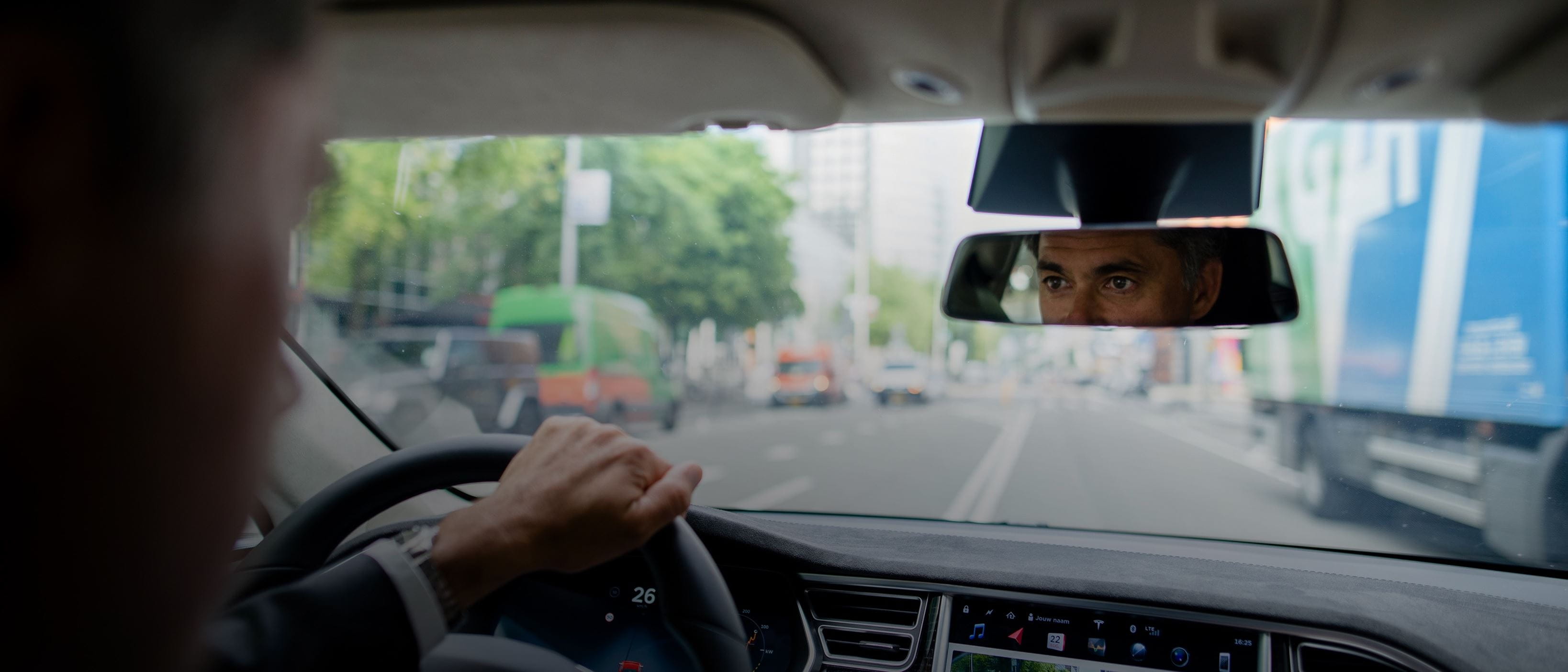 Inside car - man driving - focus on reflection in rear view mirror