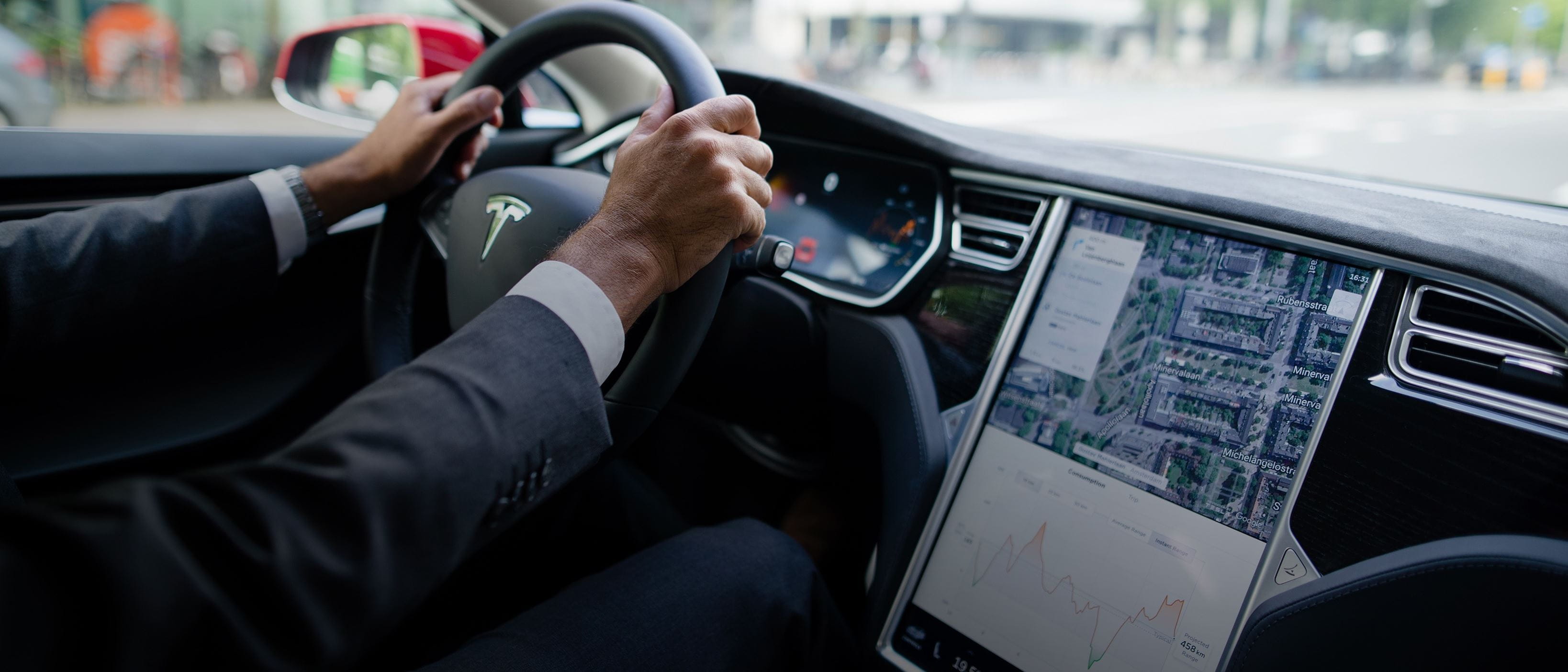 Man driving Tesla- close up of hands and car interior