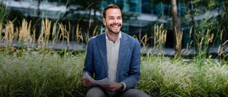 Man in centre sitting surrounded by grass - with paper