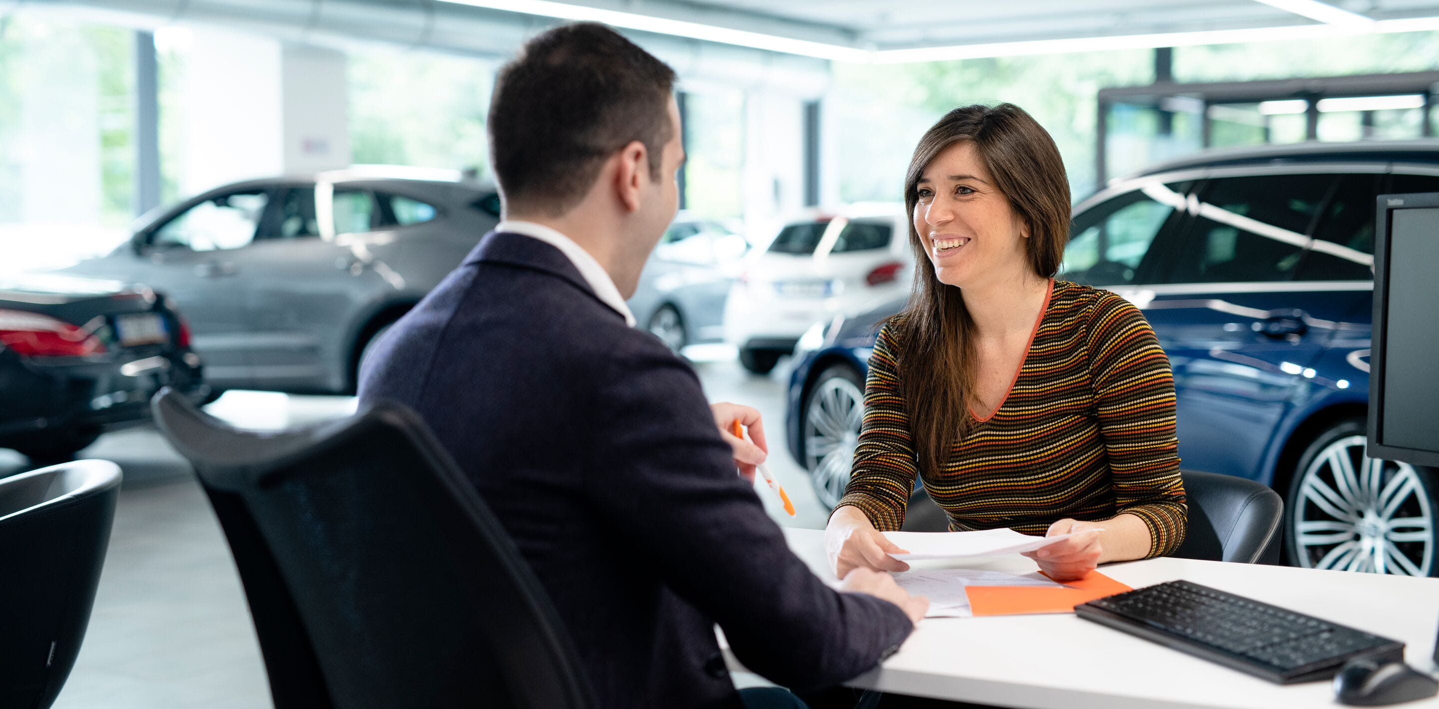 Dealership - man and woman signing papers - cars in background