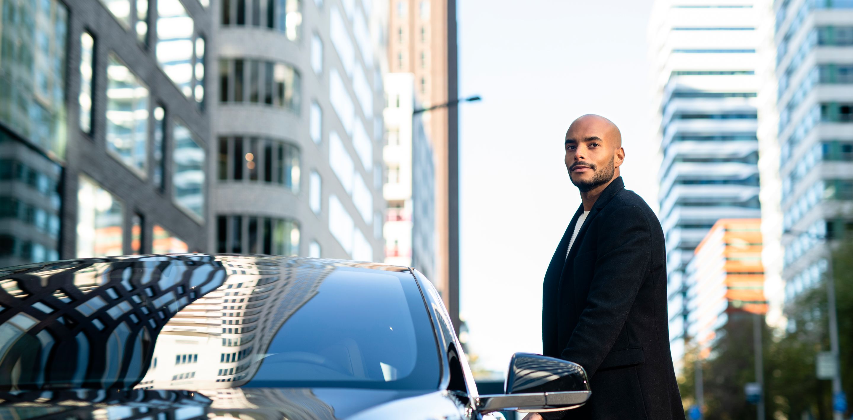 Man on city street next to car