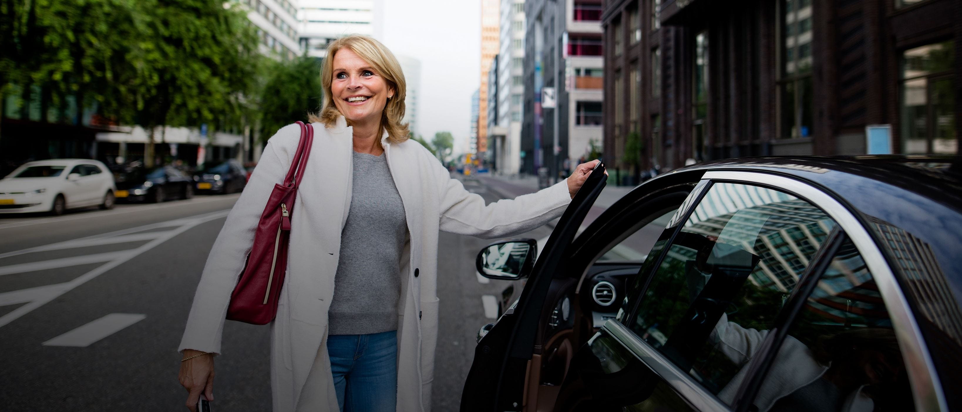 Happy woman on city street getting into car