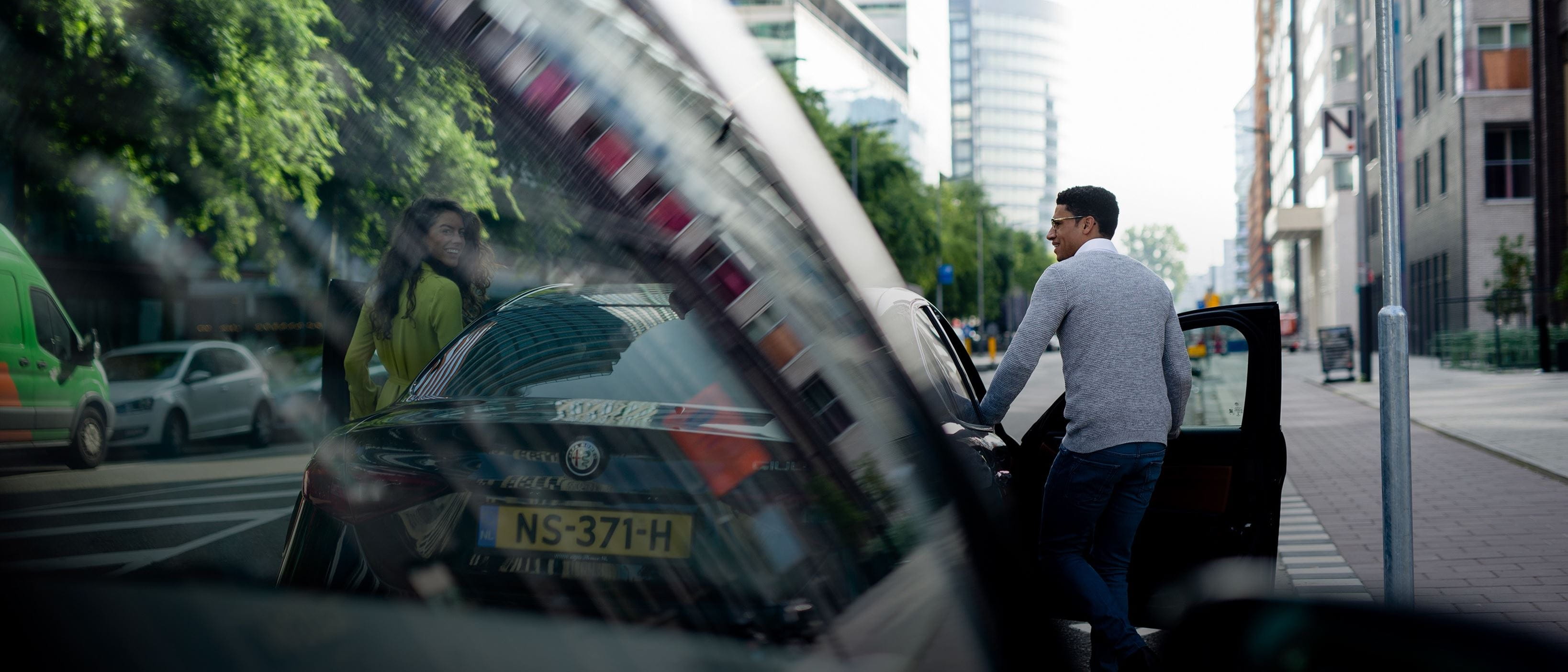 Man and woman getting into car on city street